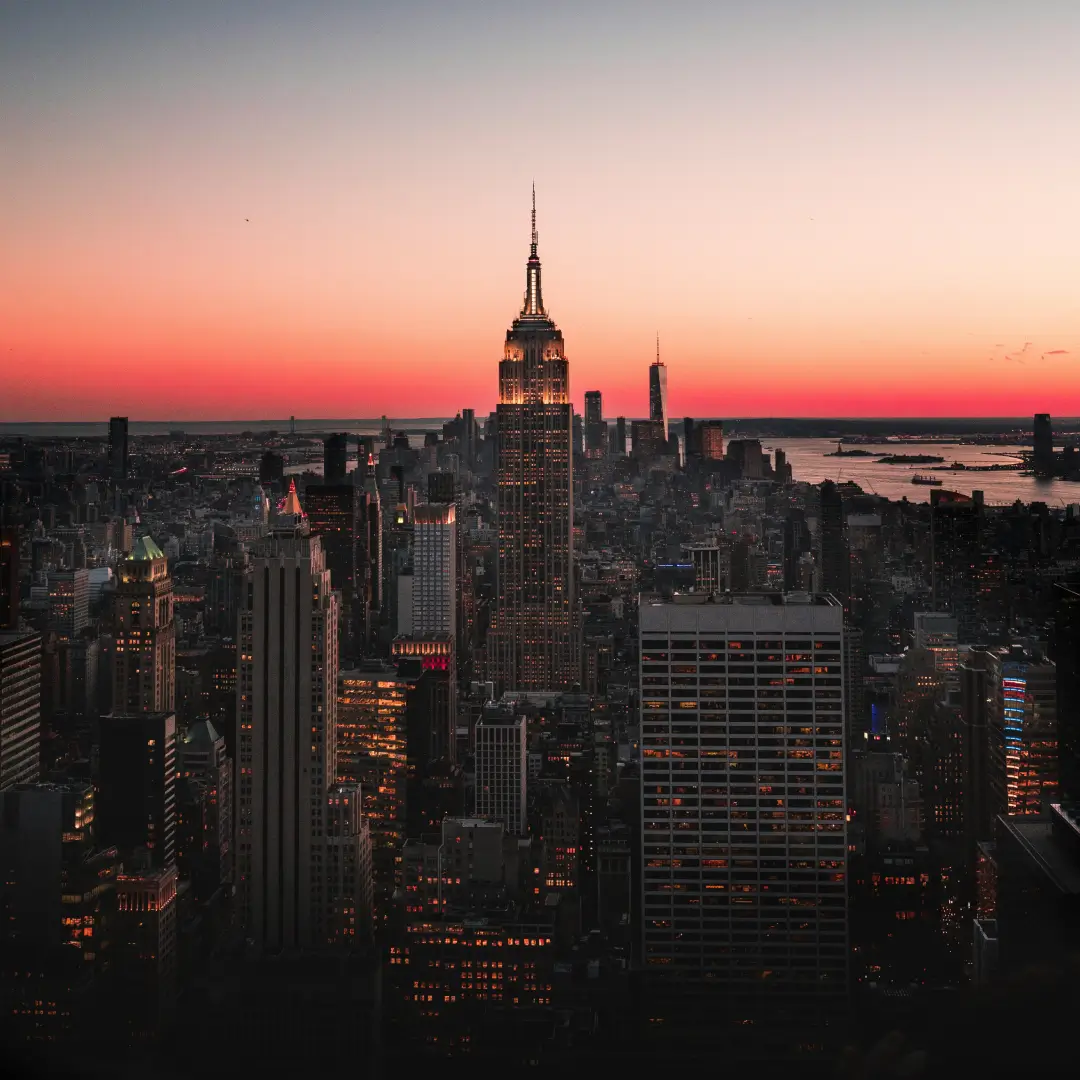 Sunset over a city skyline with prominent skyscrapers.